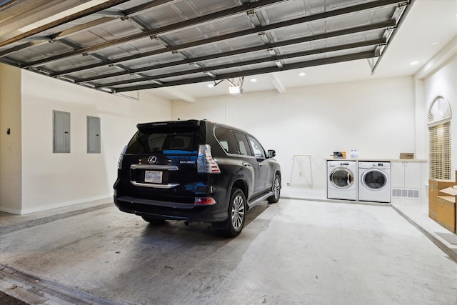 garage with a garage door opener, electric panel, visible vents, and washing machine and clothes dryer