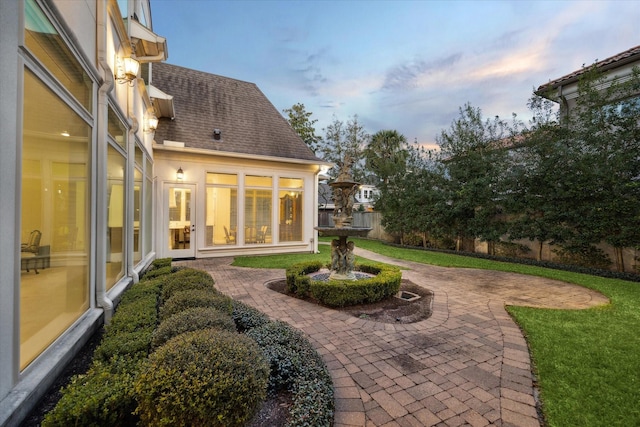 exterior space featuring a shingled roof, fence, and a patio