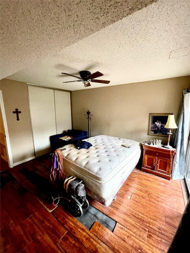 bedroom featuring hardwood / wood-style flooring, ceiling fan, a closet, and a textured ceiling