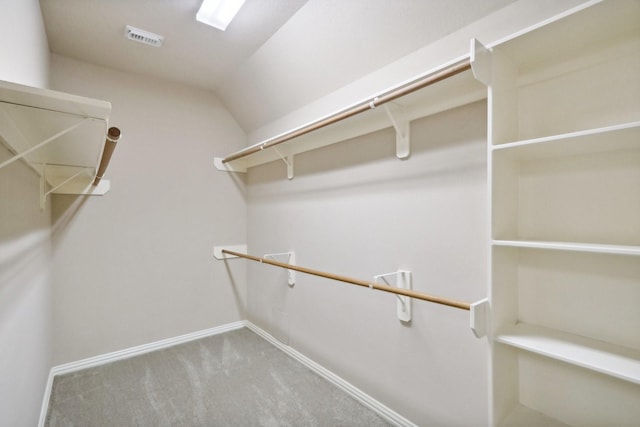 walk in closet with vaulted ceiling, carpet flooring, and visible vents