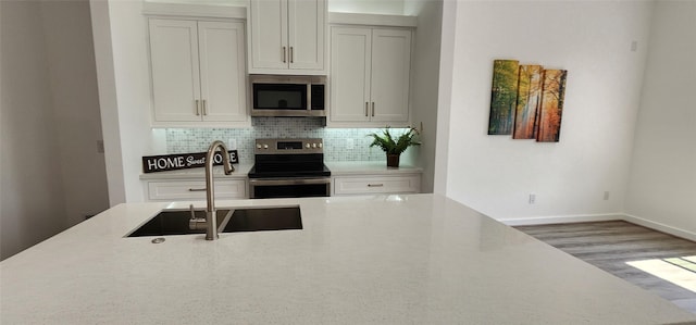 kitchen with wood-type flooring, appliances with stainless steel finishes, sink, and tasteful backsplash