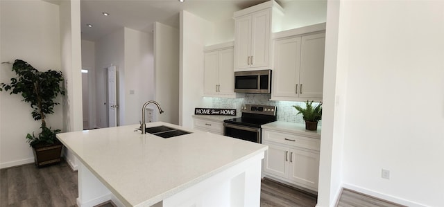 kitchen with sink, stainless steel appliances, a kitchen island with sink, and white cabinets