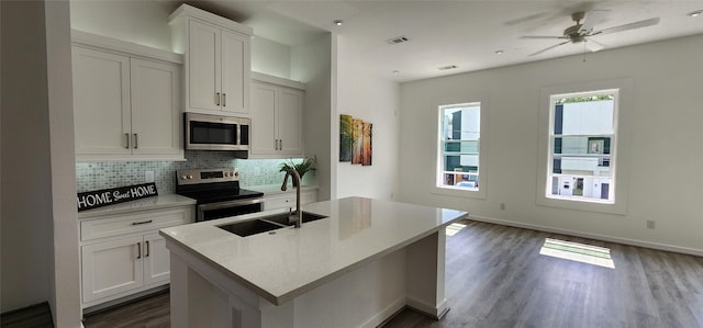 kitchen with sink, stainless steel appliances, white cabinets, a kitchen island with sink, and decorative backsplash