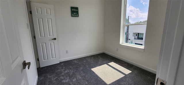 unfurnished room featuring dark carpet