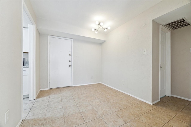 interior space featuring light tile patterned floors, baseboards, visible vents, and a chandelier