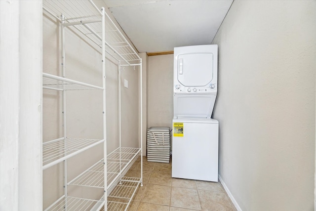 washroom with laundry area, light tile patterned floors, baseboards, and stacked washer and clothes dryer