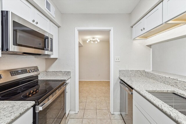 kitchen with stainless steel appliances, white cabinets, visible vents, and light stone countertops