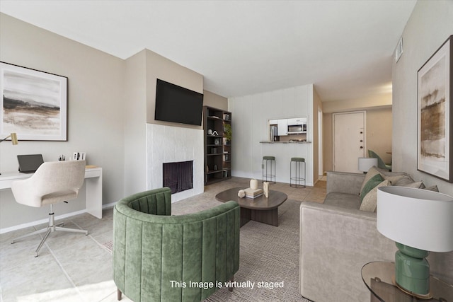 living area with light tile patterned floors, a fireplace, visible vents, and baseboards