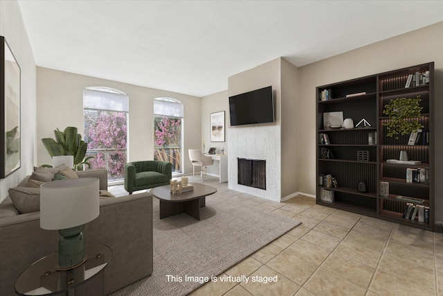 living area featuring a tiled fireplace and light tile patterned flooring