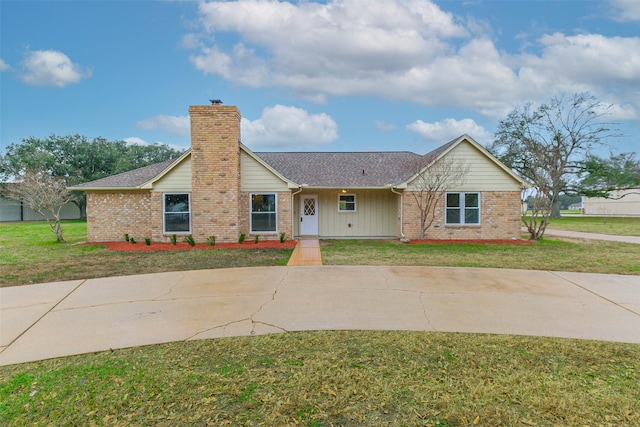 ranch-style house with roof with shingles, brick siding, a chimney, and a front yard