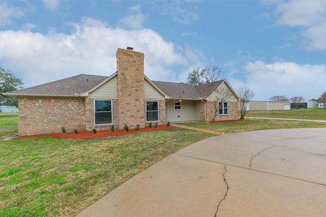 ranch-style home with brick siding, a chimney, a front yard, and a shingled roof