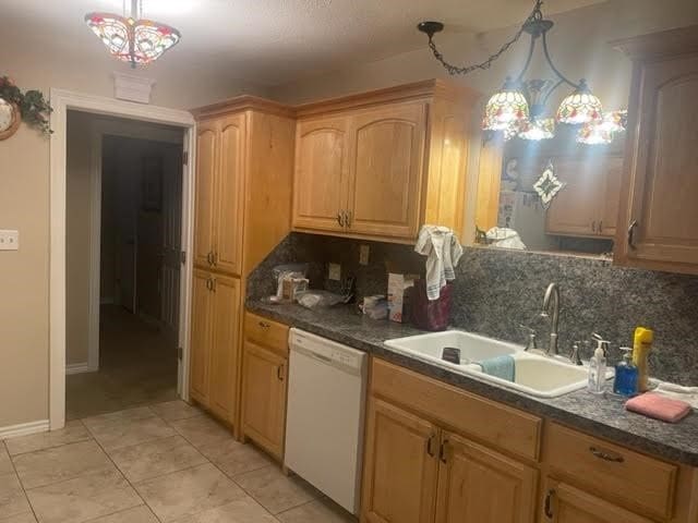 kitchen featuring sink, dishwasher, tasteful backsplash, and decorative light fixtures