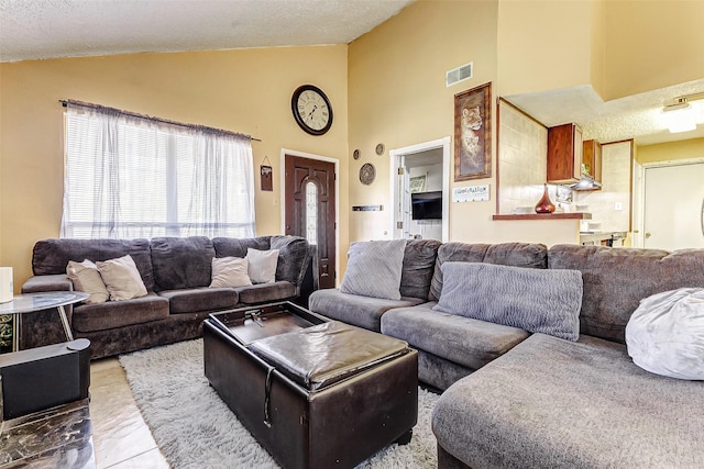 living room featuring high vaulted ceiling and a textured ceiling