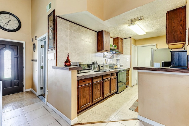 kitchen with refrigerator, black electric range, a textured ceiling, and light tile patterned flooring