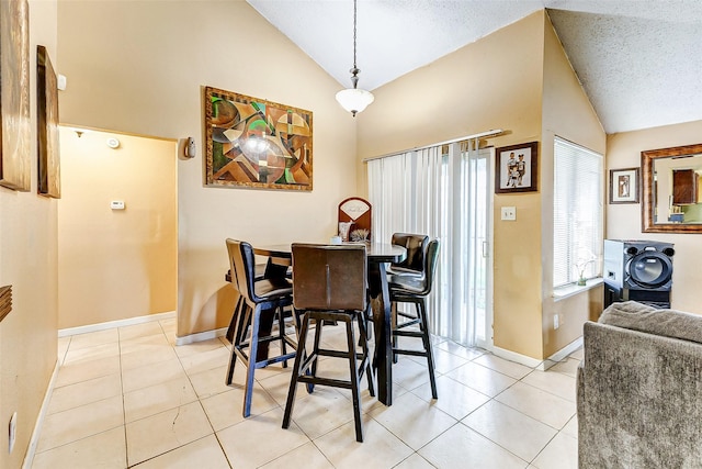 dining space featuring light tile patterned floors, high vaulted ceiling, and a textured ceiling