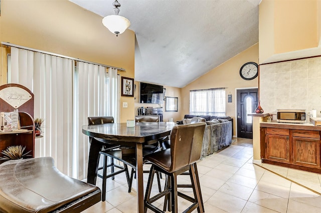 tiled dining area featuring vaulted ceiling