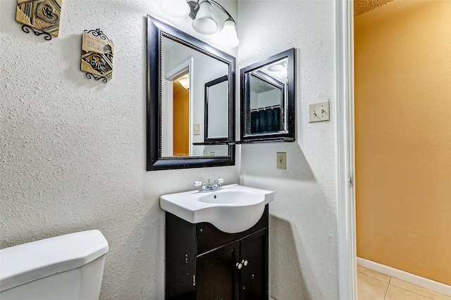 bathroom with toilet, vanity, and tile patterned flooring