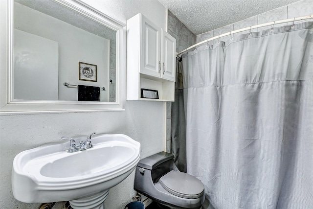 bathroom featuring a textured ceiling, toilet, sink, and a shower with shower curtain