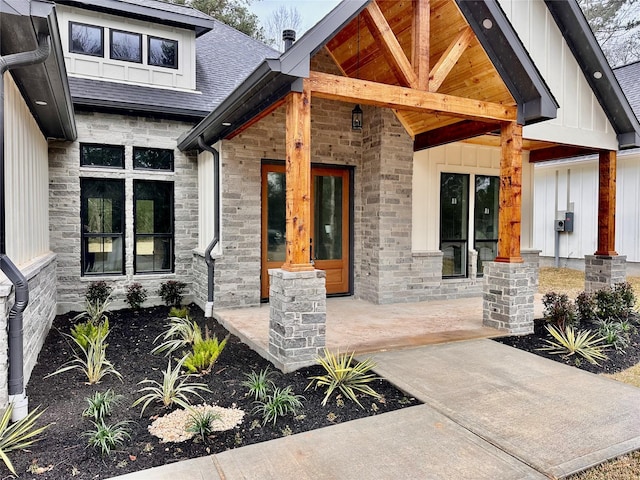 property entrance with stone siding, board and batten siding, and roof with shingles