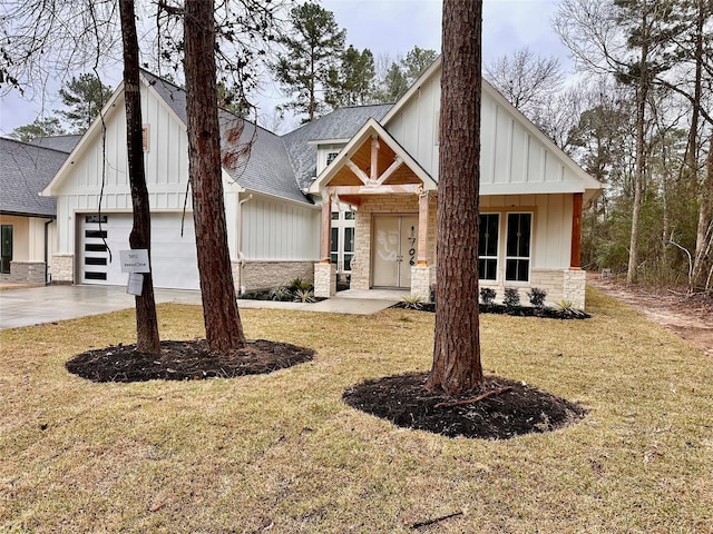 modern inspired farmhouse featuring stone siding, a front lawn, board and batten siding, and roof with shingles