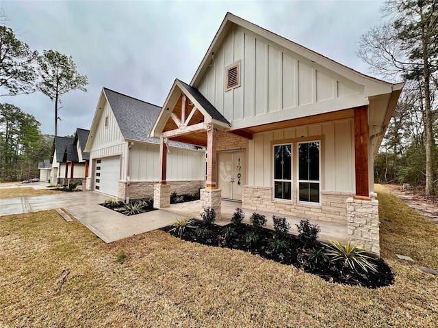 view of front facade featuring stone siding, a shingled roof, board and batten siding, and concrete driveway