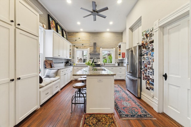 kitchen featuring a breakfast bar area, high end refrigerator, light stone counters, a center island, and sink