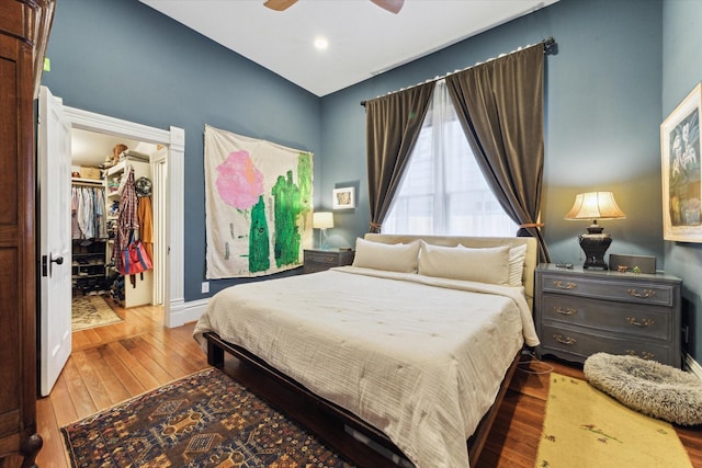 bedroom featuring hardwood / wood-style floors, ceiling fan, a closet, and a walk in closet