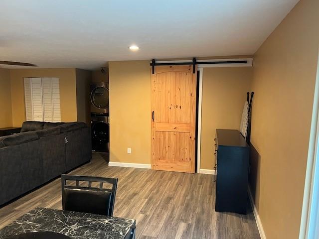 living room featuring a barn door, stacked washer / dryer, and hardwood / wood-style floors