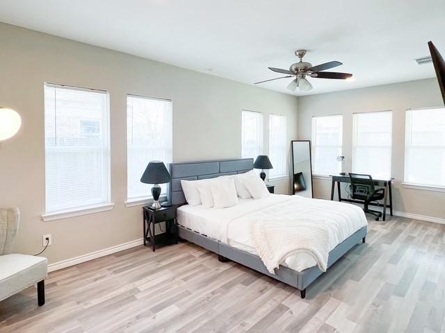 bedroom featuring multiple windows, light hardwood / wood-style flooring, and ceiling fan