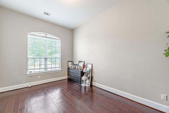 spare room with baseboards, visible vents, and wood finished floors