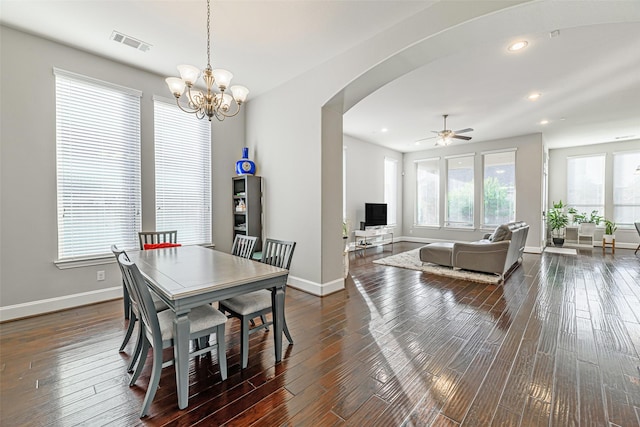 dining space featuring arched walkways, dark wood-style flooring, visible vents, and baseboards