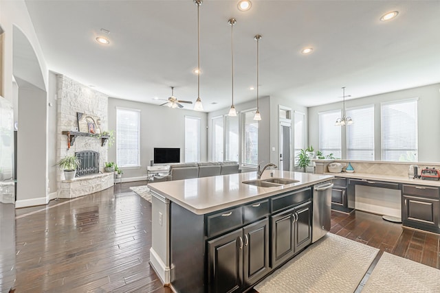 kitchen with a fireplace, light countertops, dark wood-type flooring, a sink, and an island with sink