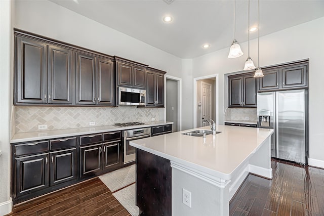 kitchen featuring appliances with stainless steel finishes, dark wood-style flooring, light countertops, pendant lighting, and a sink