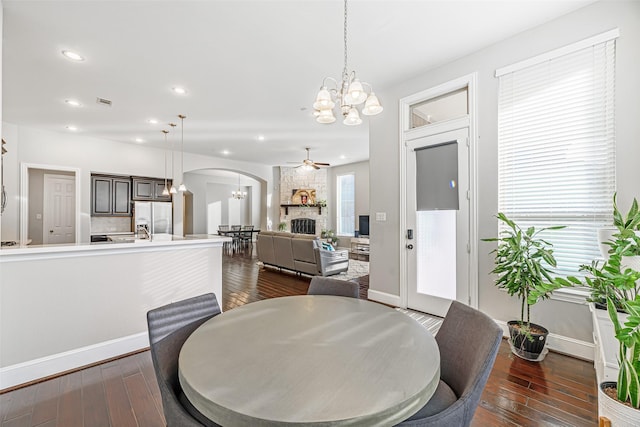 dining room with arched walkways, dark wood-type flooring, ceiling fan with notable chandelier, and recessed lighting