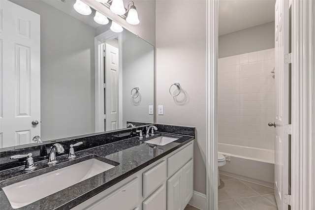 bathroom with double vanity, a sink, toilet, and tile patterned floors