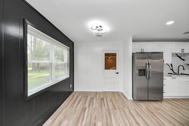 kitchen with white cabinets, light wood-type flooring, sink, and stainless steel fridge with ice dispenser