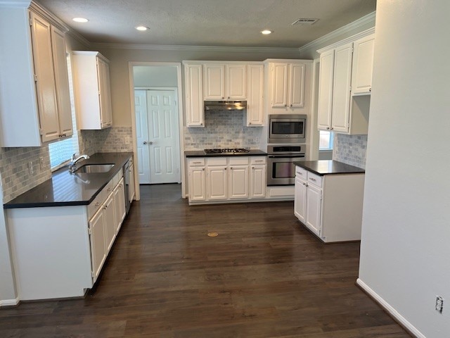 kitchen featuring stainless steel appliances, dark hardwood / wood-style flooring, sink, white cabinets, and crown molding