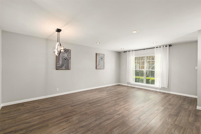 spare room featuring dark hardwood / wood-style floors and a notable chandelier