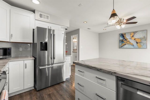 kitchen featuring hanging light fixtures, light stone countertops, appliances with stainless steel finishes, white cabinets, and dark hardwood / wood-style floors