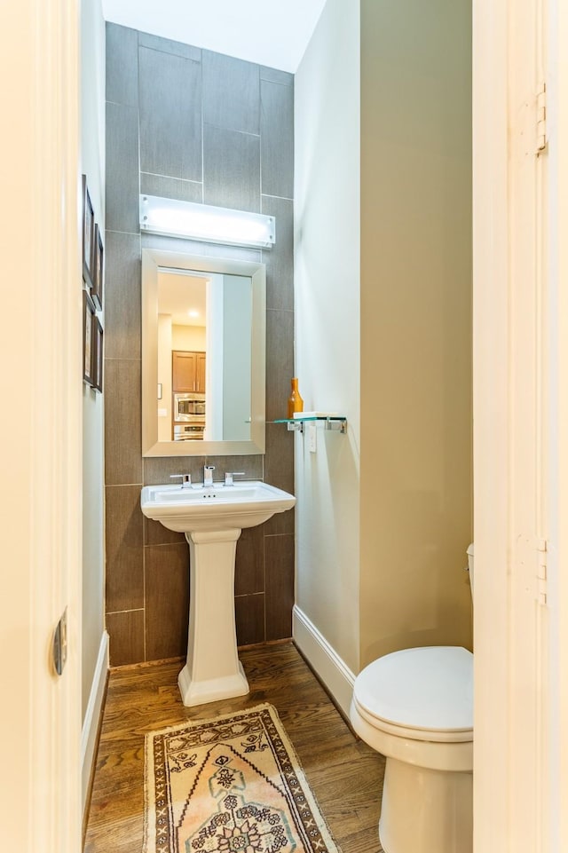 bathroom with sink, toilet, tile walls, and wood-type flooring