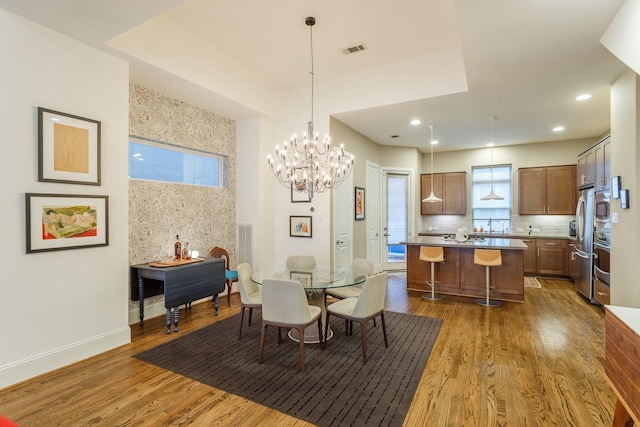 dining space with hardwood / wood-style flooring and an inviting chandelier