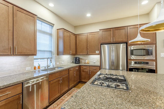 kitchen with appliances with stainless steel finishes, light stone counters, decorative backsplash, pendant lighting, and sink