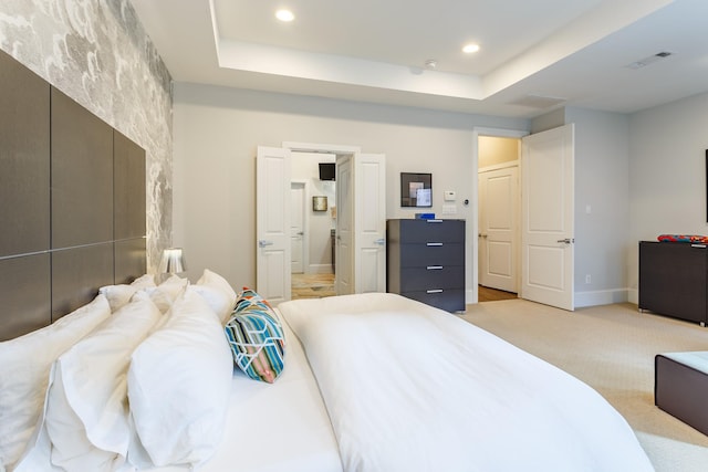 bedroom featuring a tray ceiling and light colored carpet