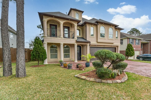 view of front of home featuring stucco siding, a front yard, fence, a balcony, and driveway