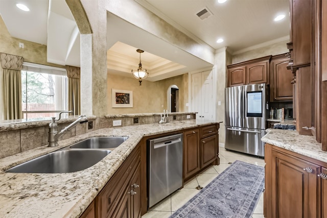 kitchen featuring appliances with stainless steel finishes, decorative light fixtures, a sink, and light stone counters