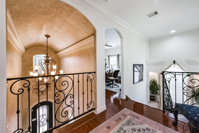 hall with arched walkways, vaulted ceiling, a notable chandelier, and dark wood finished floors