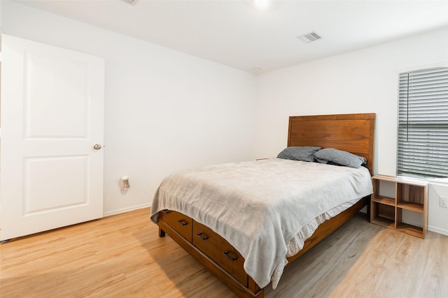 bedroom featuring light wood-style floors, visible vents, and baseboards