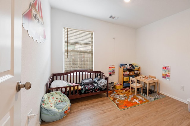 bedroom featuring wood finished floors, visible vents, and baseboards