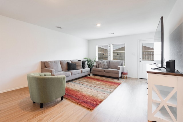 living room featuring visible vents, baseboards, and wood finished floors