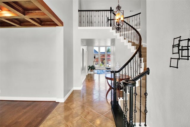 entryway featuring coffered ceiling, light tile patterned floors, a notable chandelier, beamed ceiling, and a towering ceiling